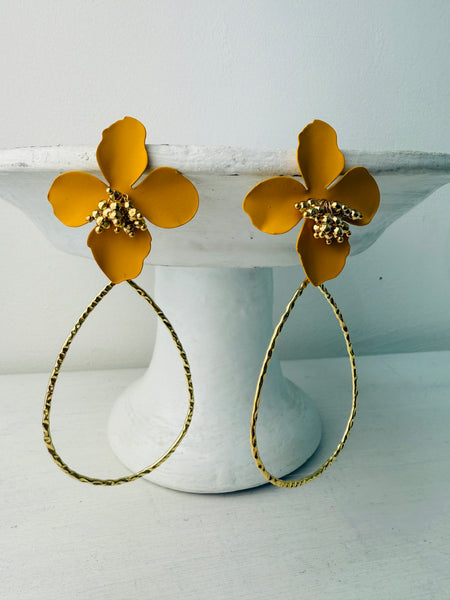 A pair of yellow floral design earrings with a golden drop pendant.