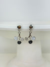 White and grey floral enamel drop earrings with crystal effect glass stones on a silver-tone branch design, dispayed on a white background.