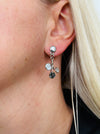 White and grey floral enamel drop earrings with crystal effect glass stones on a silver-tone branch design, dispayed on a model.