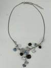 White and dark grey floral enamel necklace with crystal effect glass stones an a silver-tone chain, displayed on a table.