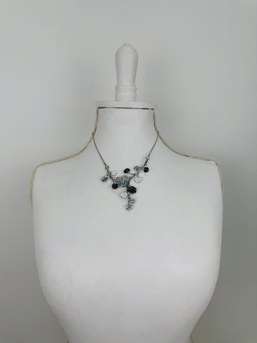 White and dark grey floral enamel necklace with crystal effect glass stones an a silver-tone chain, displayed on a mannequin.