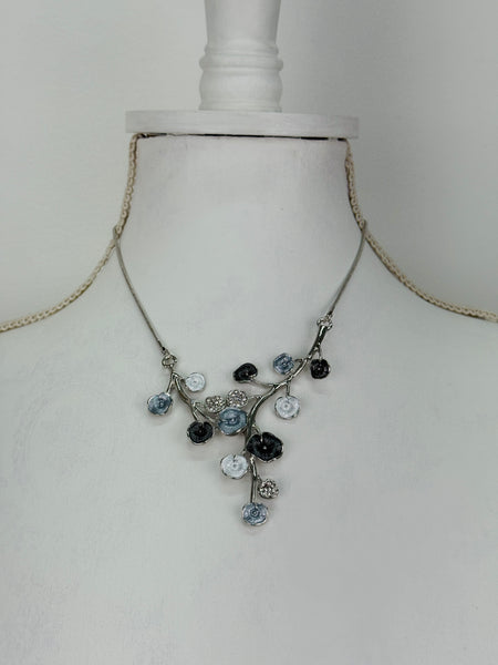 White and dark grey floral enamel necklace with crystal effect glass stones on a silver-tone chain, displayed on a mannequin.