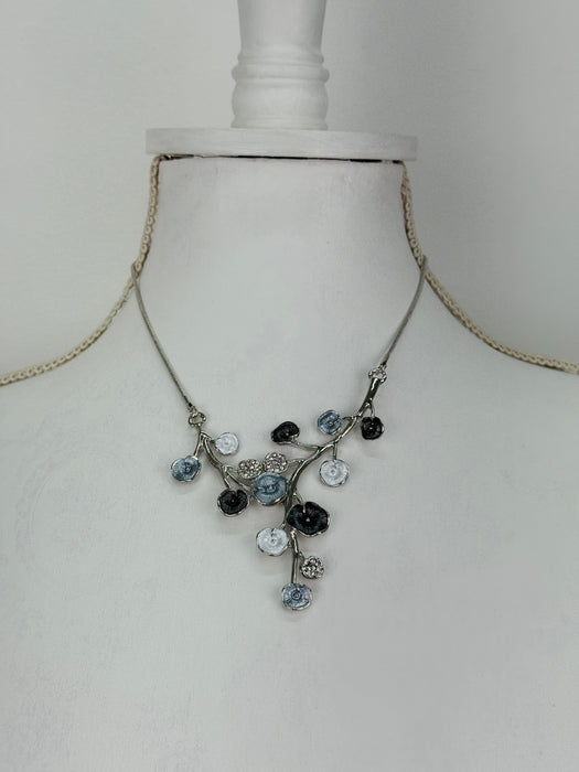 White and dark grey floral enamel necklace with crystal effect glass stones on a silver-tone chain, displayed on a mannequin.