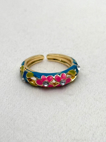 Gold ring with colorful band and pink flower design on a white background