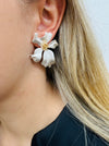 Elegant pearl white flower stud earrings with a gold-tone centre, displayed on a model.