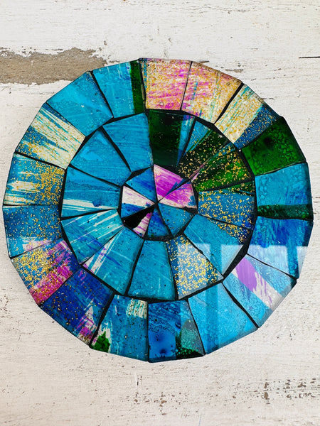 Hand-painted Galaxy mosaic coaster featuring blue, purple and green glass pieces on an MDF base, photographed from above on a light surface.