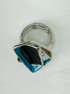 Silver-tone stretch ring with layered gunmetal and blue enamel geometric shapes.