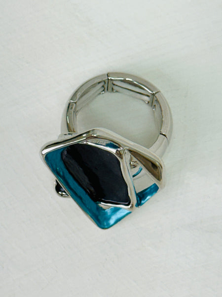Silver-tone stretch ring with layered gunmetal and blue enamel geometric shapes.