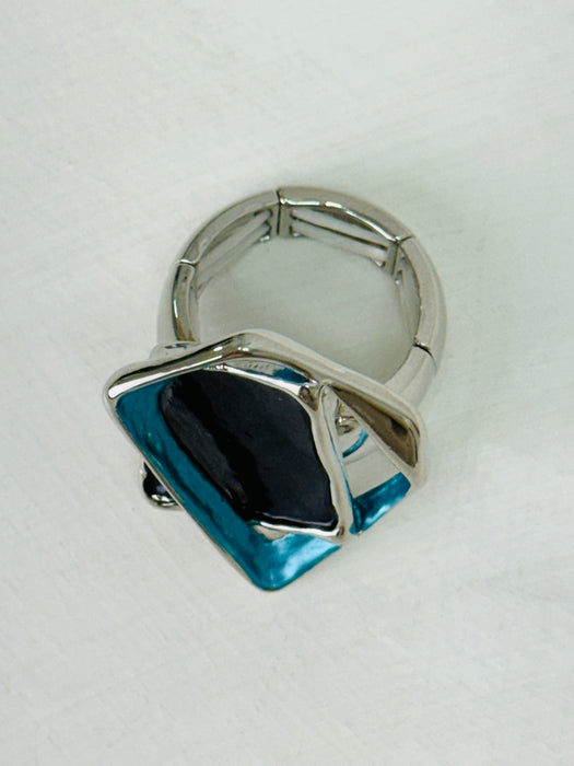 Silver-tone stretch ring with layered gunmetal and blue enamel geometric shapes.