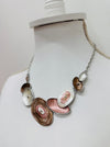Geometric statement necklace with silver tone chain and enamelled oval elements in bronze and pearl shades displayed on a mannequin.
