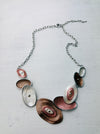 Geometric statement necklace with silver tone chain and enamelled oval elements in bronze and pearl shades displayed on a white background.