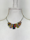 Multicoloured geometric statement necklace with rectangular enamel shapes in metallic gunmetal, bronze, gold, lilac and lemon green, displayed on a mannequin.