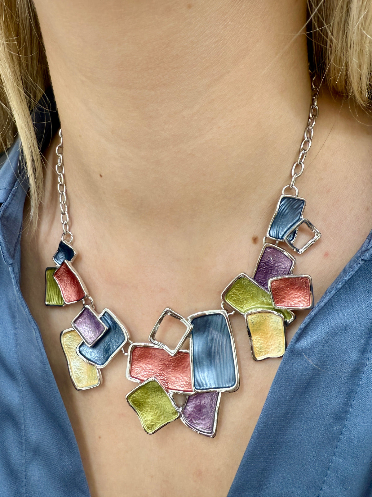 A person wearing a multicolored geometric patterned necklace with silver-tone metal links.