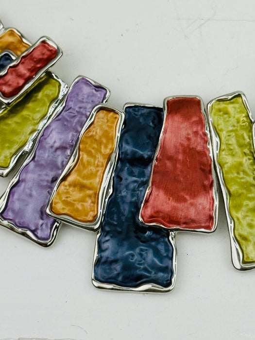 Close-up of colourfu enamel necklace with metallic panels in gunmetal, bronze, gold, lilac and lime tones.