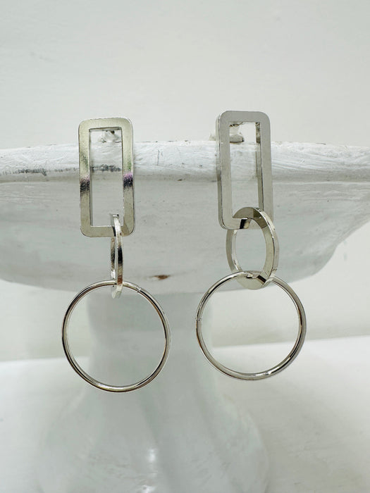 front view of geometric silver drop earrings with rectangular and circular linked shapes