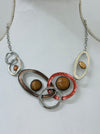 Geometric statement necklace with enamelled metal rings displayed on a mannequin.