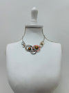 Geometric statement necklace with enamelled metal rings displayed on a mannequin.