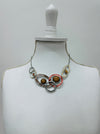 Geometric statement necklace with enamelled metal rings displayed on a mannequin.