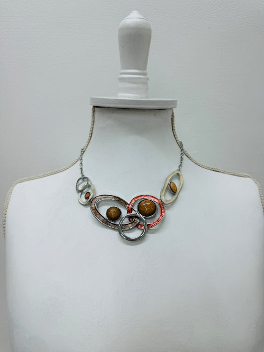 Geometric statement necklace with enamelled metal rings displayed on a mannequin.