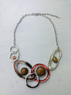 Geometric statement necklace with enamelled metal rings displayed on a white background.