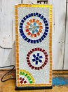 Close-up of multicoloured mosaic square lamp switched off on rustic wooden surface against white background.