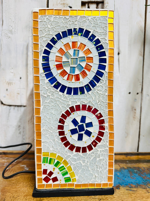 Close-up of multicoloured mosaic square lamp switched off on rustic wooden surface against white background.