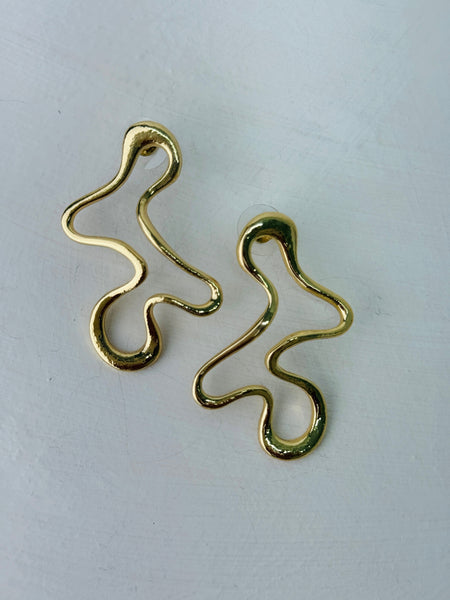 Gold abstract earrings on a light gray background