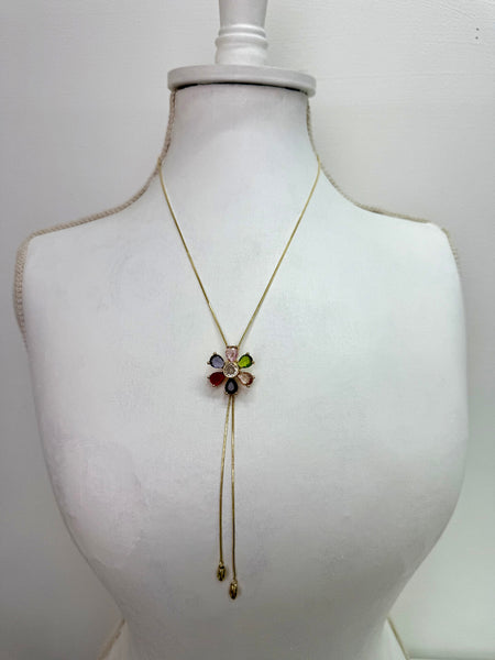Gold necklace with a colorful flower pendant on a mannequin bust against a white background