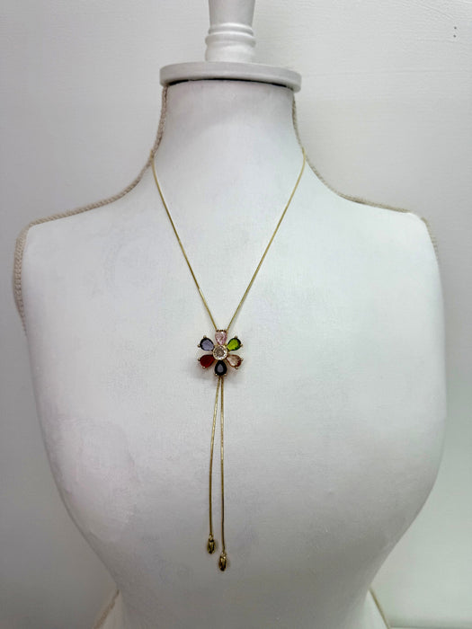 Gold necklace with a colorful flower pendant on a mannequin bust against a white background