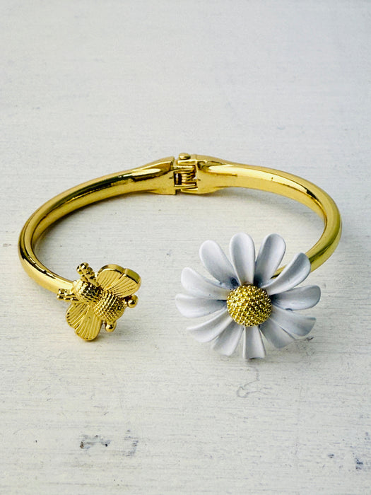 gold tone bangle bracelet with bee and white daisy enamel detail