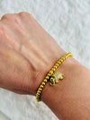 Gold bracelet with elephant charm on a wrist against a white background