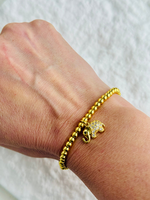 Gold bracelet with elephant charm on a wrist against a white background