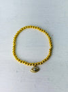 Gold beaded bracelet with a charm on a white background