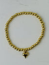 Gold beaded bracelet with a heart charm on a white background