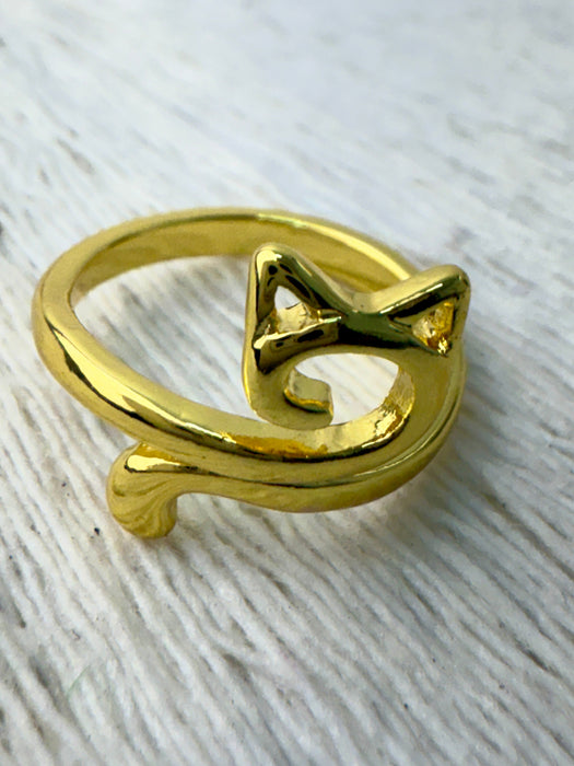 Gold cat-shaped ring on a textured white surface
