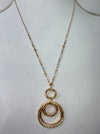 Gold necklace with circular pendant on a white background