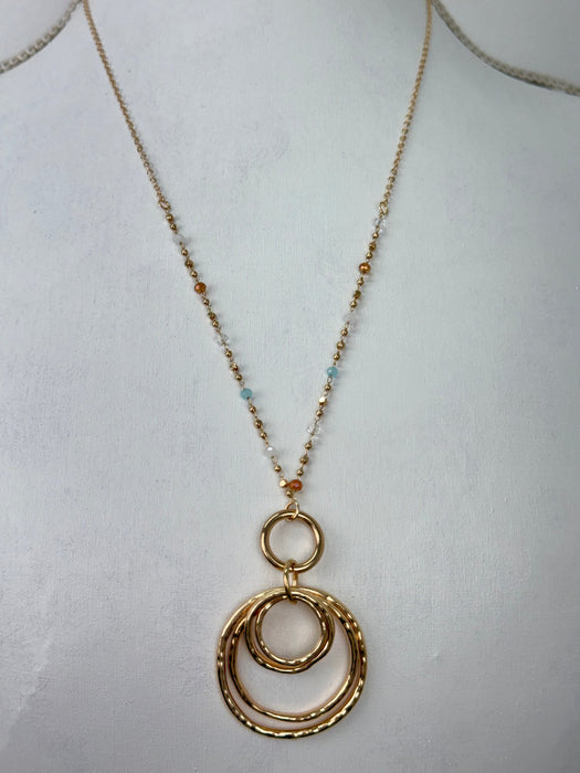 Gold necklace with circular pendant on a white background