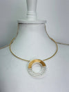 Necklace with a gold and silver circular pendant on a mannequin bust 