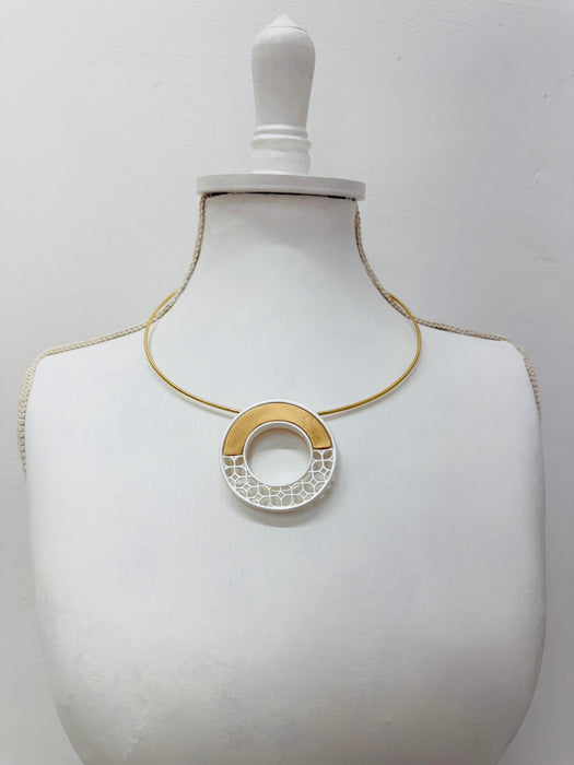 Necklace with a gold and silver pendant on a mannequin bust 
