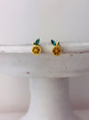 Gold earrings with green stones on a white surface