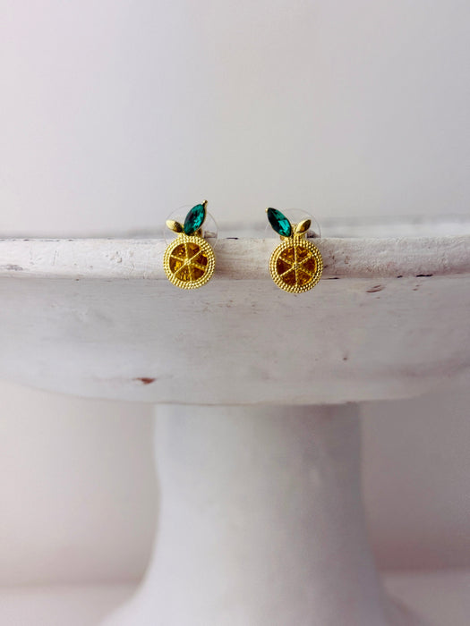 Gold earrings with green stones on a white surface