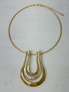 gold collar necklace with a triple-layered horseshoe-shaped metal pendant
