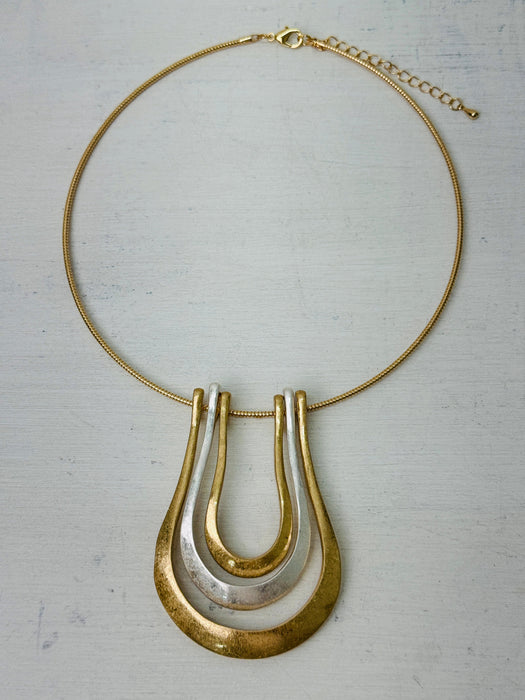 gold collar necklace with a triple-layered horseshoe-shaped metal pendant