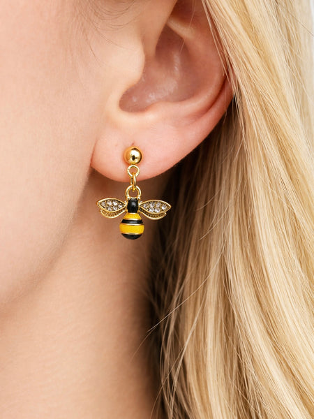 Gold bee-shaped earring worn by a person with blonde hair.