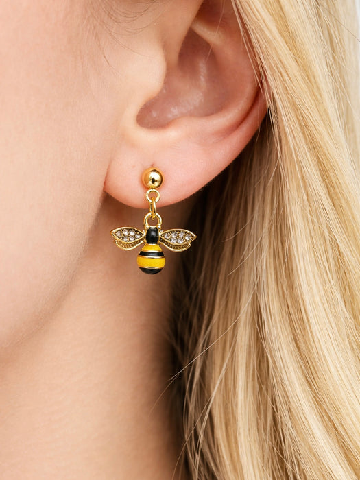 Gold bee-shaped earring worn by a person with blonde hair.
