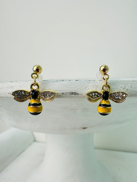 A pair of gold-colored bee earrings with black and gold accents, displayed against a white background.