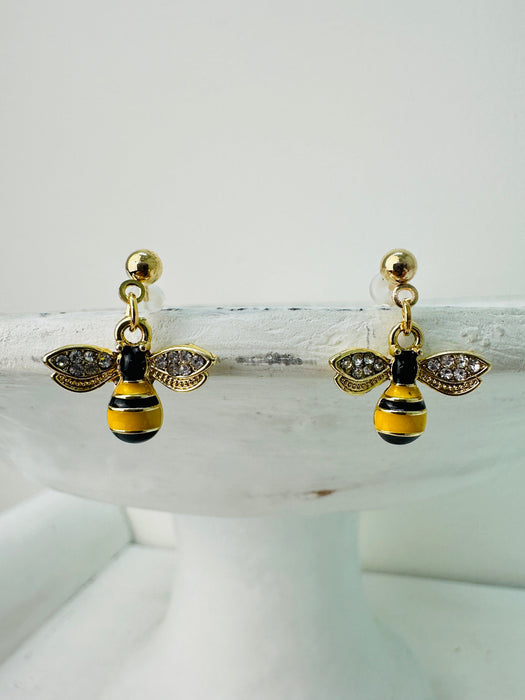 A pair of gold-colored bee earrings with black and gold accents, displayed against a white background.