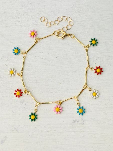 A gold tone bracelet with colorful enamel daisy charms, displayed against a white background.