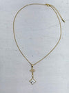 elegant gold necklace with crystal cross detail and enamel on a light gray background