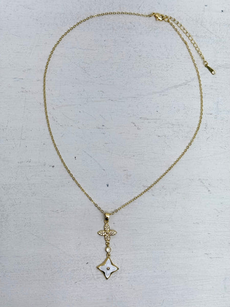 elegant gold necklace with crystal cross detail and enamel on a light gray background